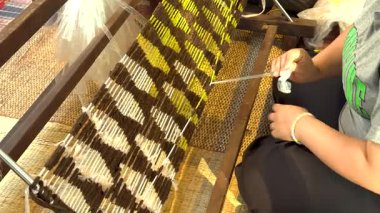 Zanaatkar dokuma tezgahında karmaşık desenler örüyor.