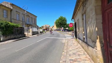 Bisikletçiler manzaralı bir Fransız kasabasında gezerler.