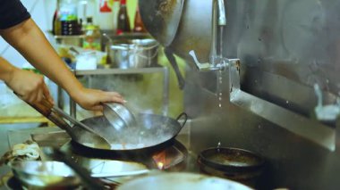 Şef, sıcak tavada ustalıkla yemek hazırlıyor.