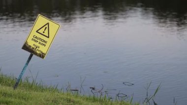 Sarı uyarı işareti usulca suda sallanıyor..
