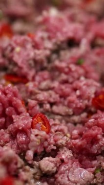 Close-up of beef stir fry preparation with red peppers in a kitchen setting