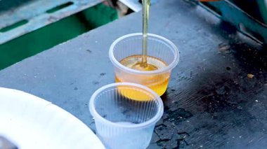 Sweet chili sauce being poured into plastic cups