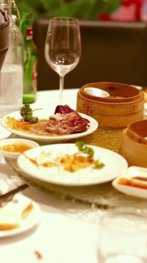 A beautifully set table with Chinese dishes, dim sum, and elegant glassware, creating a warm and inviting dining atmosphere