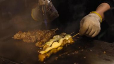 Cooking and flipping skewers on a hot grill