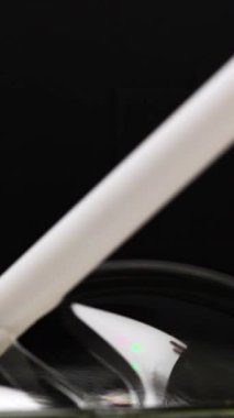 A white object interacts with soap bubbles against a dark background, highlighting reflections and surface tension