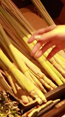 A hand selects lemongrass stalks from a well-lit supermarket display, emphasizing freshness and quality