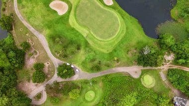Drone footage captures a lush golf course in Phuket, Thailand, showcasing vibrant greens, sand bunkers, and a serene water feature