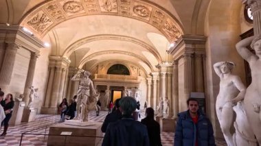 Louvre 'un heykel galerisinde yürüyen insanlar