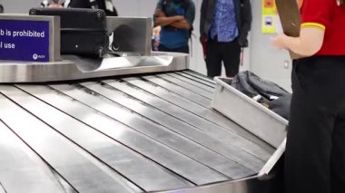 Passengers retrieve bags from airport conveyor belt