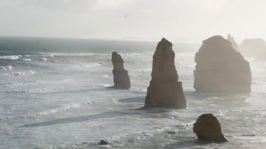 The Twelve Apostles rock formations in Melbourne, Australia, captured at sunrise with soft lighting and gentle waves