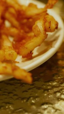 Close-up of golden, crispy fried snacks on a plate in warm lighting