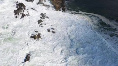 İnsansız hava aracı görüntüleri, açık gün ışığında, Avustralya 'nın Byron Körfezi' ndeki kayalık kayalıklara çarpan güçlü okyanus dalgalarını yakalar.