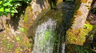 Su yosunlu taş yapının üzerinden akıyor.