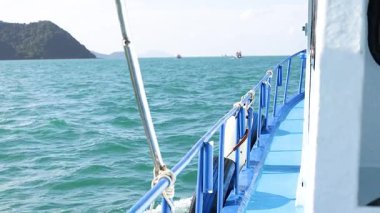 Phuket, Tayland 'da sakin bir tekne gezisi, berrak gökyüzünün altında canlı mavi sular ve uzak adalar sergiliyor.