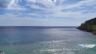 Phuket 'in kıyı şeridinden sakin bir hava manzarası, sakin okyanus suları ve parlak, berrak bir gökyüzü altında yemyeşil.