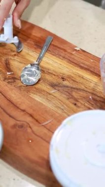 Eller titizlikle mutfak ışıklandırmasının altında ahşap bir kesme tahtasındaki yemek işlemcisini temizler.