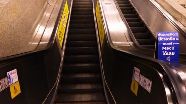 Bangkok MRT istasyonunda bir yürüyen merdiven sekansı modern mimari ve ortam aydınlatmasını vurgular.