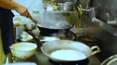 Aşçı ustalıkla mutfakta tavayla yemek pişiriyor.