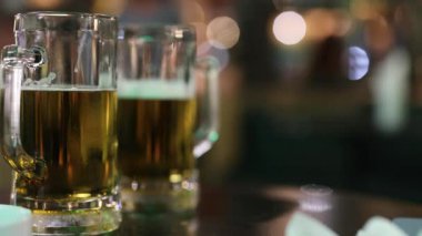 Close-up of beer glasses on a table with a blurred, ambient background, creating a warm and inviting atmosphere