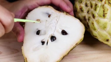Hands slicing custard apple with a knife