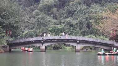 Boats passing under a bridge in a lush setting