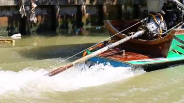 Bir tekne hareketli yüzen bir pazarda hızla ilerliyor.