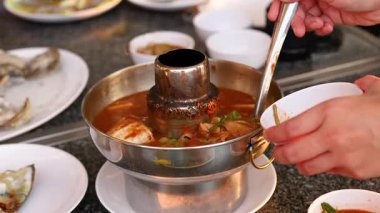 Elleri sıcak bir tencerede çorba servis ediyor.