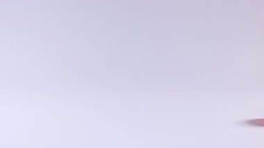 Turuncu tenis topu beyaz bir yüzeyde yuvarlanıyor.