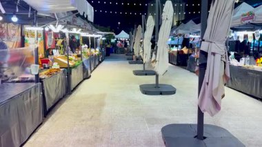 Gıda tezgahları ve ışıkları olan canlı bir gece pazarı.