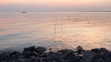 Calm sea with distant boat and sunset