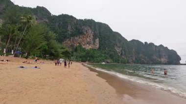 İnsanlar plajın ve manzaranın tadını çıkarıyor.