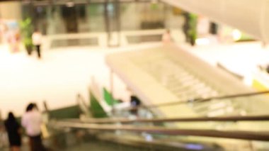 İnsanlar kalabalık bir alışveriş merkezinde yürüyen merdiven kullanıyorlar.