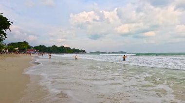 İnsanlar kumsalın ve okyanus dalgalarının tadını çıkarıyor.