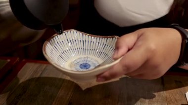 Person pouring water into a decorative bowl