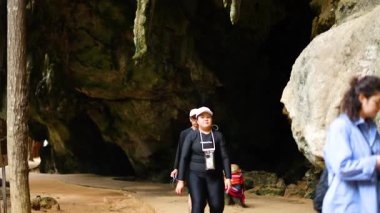 Visitors walking near a cave entrance