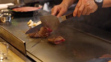 Chef expertly prepares steak and shrimp on hot grill