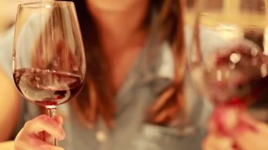 Bir insan, sıcak ve samimi bir yemek ortamında kırmızı şarabı bardağa doldurup havayı aydınlatır.