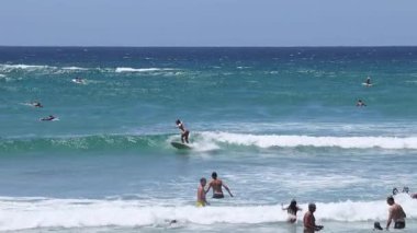 İnsanlar sahilde sörf yapmaktan ve yüzmekten hoşlanıyor.
