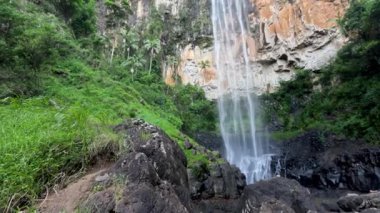 Şelale kayalık bir uçurumdan aşağı yuvarlanıyor.