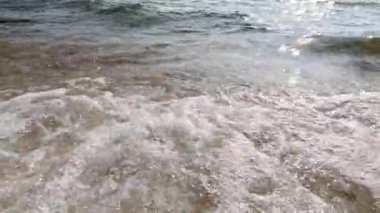 Yumuşak dalgalar kumsalda yuvarlanıyor