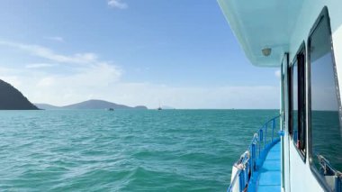 Phuket, Chalong Körfezi 'ndeki turkuaz sularda sakin bir tekne gezintisi, açık gökyüzü ve uzak adalarla.