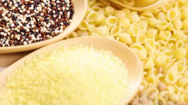 Kinoa, mercimek, kuskus ve makarnanın detaylı bir görünümü, parlak ışıklandırmada dokuları ve renkleri vurguluyor