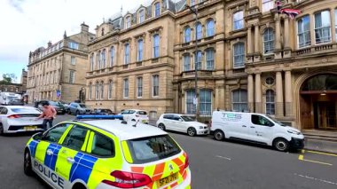 Polis arabası ve minibüsleri tarihi binanın önünde.