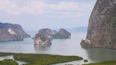 Tayland, Phang Nga 'da berrak bir gökyüzü altında yükselen kireçtaşı uçurumlarının ve sakin suların panoramik görüntüsü