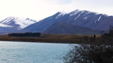 Kar kaplı dağlarla kaplı Tekapo Gölü 'nün sakin manzarası yumuşak ışık altında, doğal güzellik ve sakinliği yakalıyor.