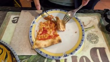 Çatal ve bıçakla pizza yiyen kişi.