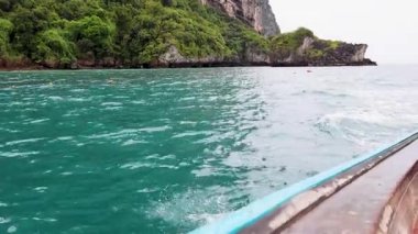 Tur teknesi yemyeşil, kayalık kıyı şeridini geçiyor.