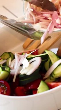 Parlak bir mutfak ortamında domatesli, salatalıklı ve soğanlı canlı bir salata.