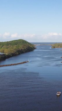 Hava görüntüleri, Brunswick Heads, Avustralya 'daki berrak gökyüzünün altında yemyeşil bir kanat tarafından çevrelenmiş sakin bir su yolunu yakalıyor.