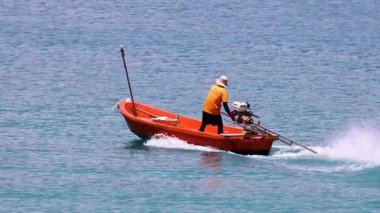 Balıkçı, uzun kuyruklu bir tekneyi Phuket sularında hızla sürüyor.